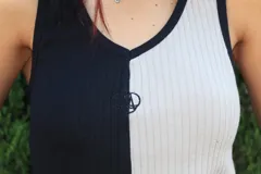 Musculosa con diseño color block, mitad negra y mitad gris claro, con cuello en V y logo bordado en el pecho.