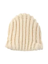 Poncho tejido a mano en lana merino color crudo, con capucha, cuello alto y flecos.