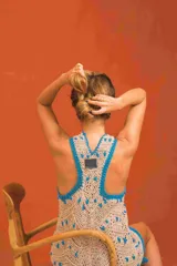 Vestido corto sin mangas elaborado en tejido de punto con patrón geométrico en tonos beige y detalles en celeste en el cuello, sisas y dobladillo.