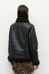 Campera tipo gamulán de símil cuero color marrón oscuro, con interior y solapas de corderito al tono. Presenta cierre frontal cruzado, bolsillos con cierre metálico y hebilla ajustable en el cuello.