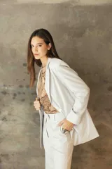 Blazer sastrero de corte recto y fit relajado, confeccionado en lino con hilos de lurex. Presenta solapas clásicas, hombreras, cierre frontal con un botón de nácar y bolsillos laterales con solapa.