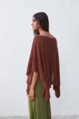 Poncho tejido color ladrillo con brillo, de corte asimétrico y cuello bote.