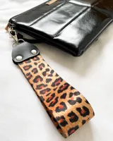 Llavero con correa de tela con estampado animal print y detalles en cuero sintético negro.