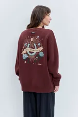 Sweater de punto color bordó, con cuello redondo, manga larga y diseño holgado. Presenta detalles bordados en hilo dorado en la zona del hombro y en el puño.