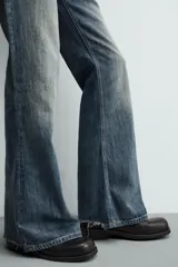 Jeans flare fit de tiro medio, confeccionados en denim de algodón color azul con efecto deslavado. Diseño ajustado en la parte superior y abierto en campana desde la rodilla, con cinco bolsillos y cierre frontal con cremallera y botón.