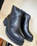 Botas de cuero negro con caña baja y suela track.