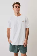 Remera blanca de manga corta y corte holgado, con cuello redondo y pequeño estampado en el pecho.
