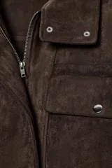 Bomber de corte oversize confeccionada en tejido efecto ante color marrón. Presenta cuello subido, cierre frontal con cremallera y botones ocultos por solapa, y bolsillos delanteros con solapa y botón.