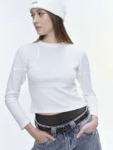 Remera de manga larga confeccionada en tela waffle color beige, con cuello redondo y costuras decorativas visibles en la parte frontal. Presenta un corte ajustado y textura en relieve.