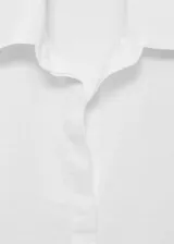 Camisa oversize blanca de lino con cierre de botones frontal, cuello camisero y mangas largas con puños abotonados.