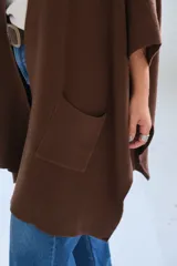 Poncho abierto de color marrón chocolate, con diseño de corte asimétrico, mangas amplias y bolsillos frontales aplicados.