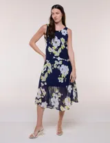 Conjunto de dos piezas en gasa azul marino con estampado floral en tonos blancos y amarillos, compuesto por un vestido midi sin mangas con forro y una capa ligera de mangas amplias.