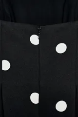 Mono largo de escote recto sin tirantes, con peplum en la cintura, perneras acampanadas y estampado de lunares.
