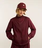 Campera deportiva femenina, modelo rompevientos, confeccionada en poliamida, con cuello alto y puños ajustados. Sin estampa, tiene cierre delantero con cremallera y recortes con hilo reflectante.