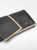 Clutch negro de piel bovina con estructura de lienzos superpuestos y cierre de solapa.