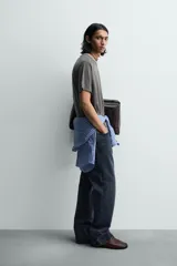 Camiseta relaxed fit color gris oscuro, confeccionada en tejido ligero de algodón con elasticidad. Presenta cuello redondo y manga ranglán corta.