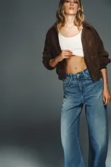 Jeans de tiro alto con corte wide leg y pernera recta. Presentan un diseño de cinco bolsillos con efecto lavado y cierre frontal mediante cremallera y botón metálico.