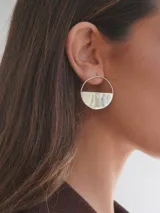 Aros colgantes plateados de diseño geométrico, formados por un aro circular con la mitad inferior sólida y texturada.