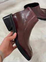 Botas cortas color bordó con punta cuadrada, suela negra y cierre lateral.