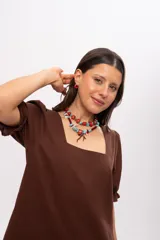 Collar corto elaborado con cuentas de turquesa reconstituida, piezas de nácar blanco, cuentas de cristal rojo y turquesa, y un dije central con forma de rama de coral.