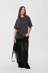 Remera oversized de manga corta y cuello redondo, de color negro con efecto acid wash y aplicación de strass en la parte superior.