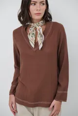 Blusa de manga larga color marrón con escote en V, destacada por sus costuras decorativas en contraste de color blanco en el cuello, puños y ruedo.