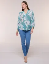 Blusa holgada de gasa texturizada color blanco con estampado de lunares negros, escote en V con botones frontales, mangas 3/4 abullonadas y puños elásticos.
