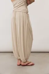 Pantalón holgado negro tipo bombacho, con cintura elástica y puños fruncidos en los tobillos.
