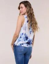 Blusa sin mangas de viscosa blanca con estampado floral en tonos azules, cuello redondo y cierre frontal parcial con botones.
