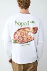 Remera de manga larga color blanco con cuello redondo y diseño de doble capa en las mangas. Presenta un estampado pequeño en el pecho con la frase 'Napoli 1990 Ciao, ci vediamo' en color verde.