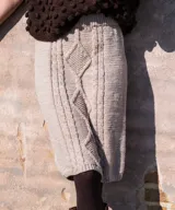 Falda midi de tiro alto tejida en lana merino color beige, con diseño de trenzas y rombos texturados en relieve.