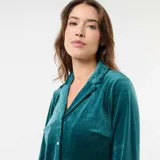 Conjunto de pijama de dos piezas en terciopelo color verde oscuro, compuesto por una camisa de manga larga con cuello solapa y botones frontales, y un pantalón largo de corte recto.