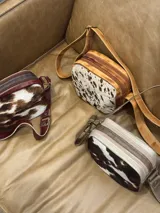 Bandolera de cuero marrón con panel frontal de piel sintética con estampado animal en tonos verde oliva y marrón. Tiene correa larga regulable, cierre superior con cremallera y forro interior.