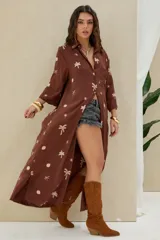 Camisola larga de color marrón con bordados en tono crudo de palmeras y soles, mangas largas y cierre frontal con botones.