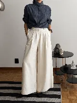 Pantalón de tiro alto con corte wide leg y diseño de pinzas frontales. Confeccionado en lino natural, presenta una silueta amplia y fluida con bolsillos laterales.