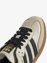 Zapatillas Adidas Samba OG de cuero color crema con detalles en negro y suela de goma marrón.