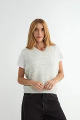 Chaleco de punto color crema con escote en V, sin mangas y diseño decorado con pequeñas perlas aplicadas en toda la superficie.