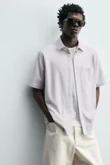 Camisa azul marino de corte regular fit confeccionada en tejido fluido de algodón y lino, con cuello solapa, manga corta, bolsillo aplicado en el pecho y cierre frontal con botones.