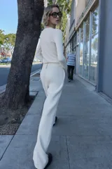 Pantalón blanco de tiro alto con pernera recta y pinzas marcadas en el frente. Cierre frontal con botón metálico dorado.