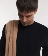 Suéter de hombre color negro, tejido en punto con textura trenzada en patrón de rombos. Presenta cuello redondo, puños y bajo acanalados.