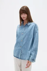 Campera de jean de corte holgado, con cuello camisero, cierre frontal con botones metálicos y mangas largas.