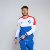 Buzo de cuello redondo Umbro del Club Nacional de Football. Diseño tricolor con cuerpo superior blanco, franja central azul y detalles en rojo en hombros y puños. Incluye logo de Umbro y escudo del club en el pecho.