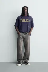 Remera de manga corta con corte relajado, confeccionada en tejido de algodón con textura tipo waffle. Presenta un efecto de lavado desgastado en color azul oscuro y estampado gráfico a contraste en el frente.