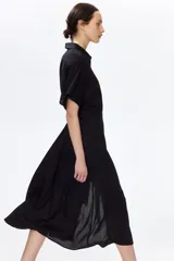 Vestido midi negro con cuello camisero, botonadura frontal de botones dorados, mangas cortas y cinturón ajustable para atar en la cintura.