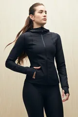 Campera deportiva negra de calce entallado, con cierre frontal completo, capucha integrada y mangas largas con puños envolventes. Presenta costuras estratégicas que estilizan la silueta y bolsillos laterales funcionales.