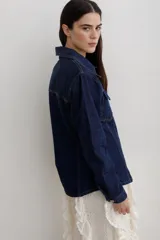 Chaqueta de denim color marrón, con corte entallado en la cintura, cierre frontal con botones metálicos y bolsillos superiores con solapa.