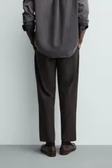 Pantalón de corte regular fit, color negro, confeccionado en tejido elástico. Presenta cintura elástica, cierre frontal con cremallera y botón, bolsillos laterales y bolsillos traseros de vivo.
