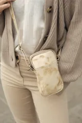 Bolso bandolera pequeño de cuero color natural con efecto desgastado, cierre superior, bolsillo interno, bolsillo externo y correa ajustable.