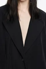 Chaqueta de corte sastre color negro, con cuello de solapas, cierre frontal con botones y manga larga recta. Presenta bolsillos laterales con solapa.