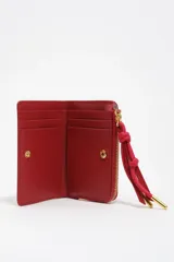 Billetera pequeña de estructura rígida, color negro, con estampado frontal en color dorado con la palabra "BIMBA". Posee cierre superior con tirador de tela amarillo mostaza.